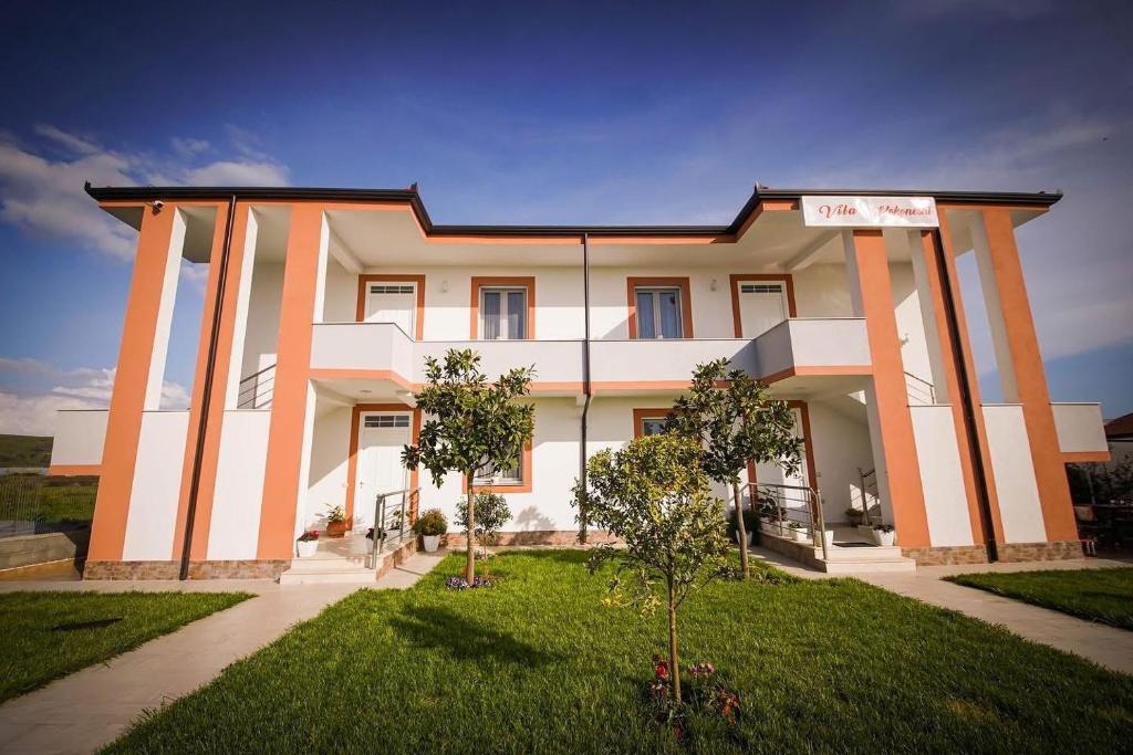a large house with pillars in a yard at Villa Kokoneshi in Divjakë
