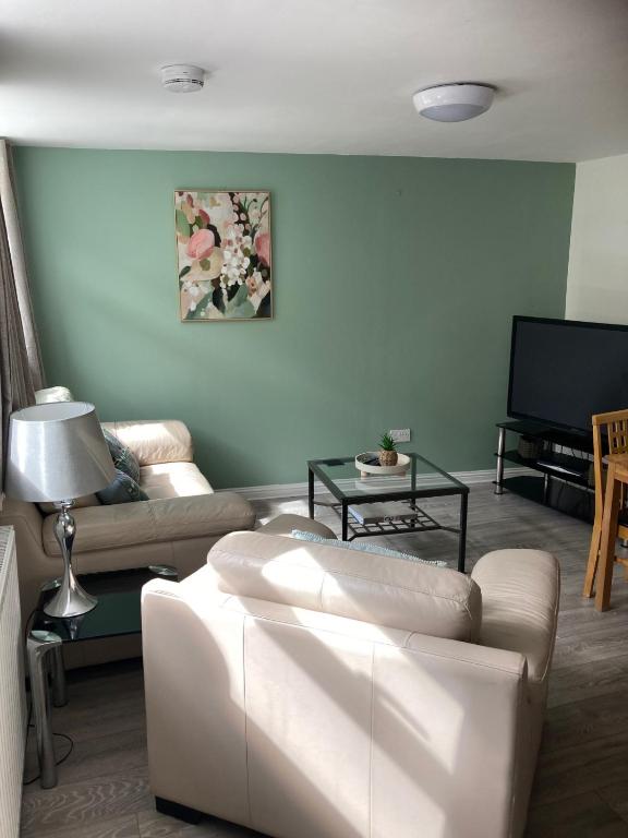 a living room with white furniture and a flat screen tv at Gallowgate Square Apartments in Largs