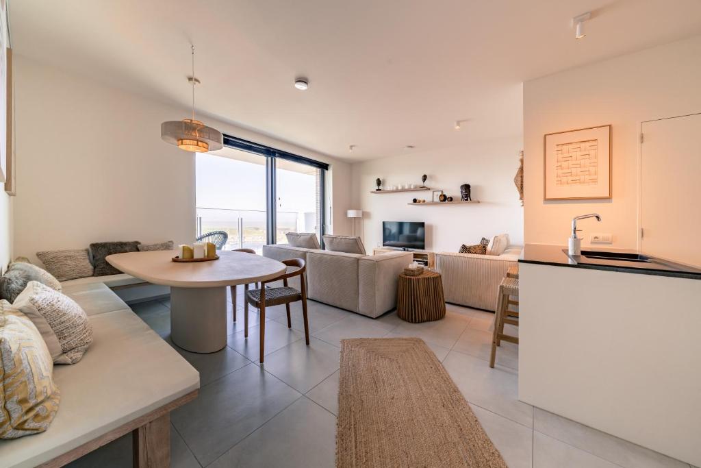 a kitchen and living room with a table and a couch at Top uitzicht luxe appartement DUNES met terras POOL & GYM in Ostend