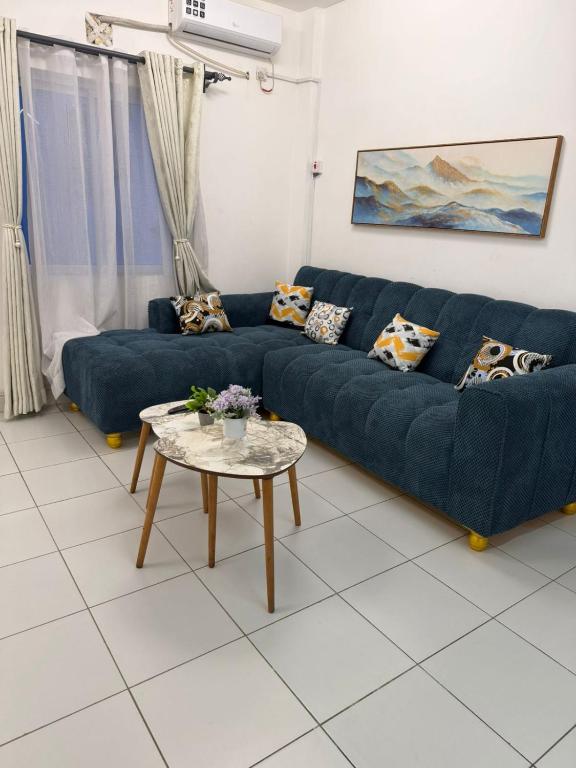 a living room with a blue couch and a table at Stylish 2BR Pool, Gym Garden in Mombasa