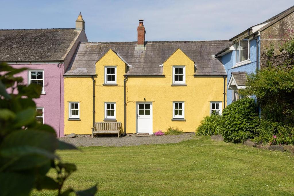 a yellow house with a bench in a yard at 2 Bed in St. Brides oc-k30489 in Saint Brides
