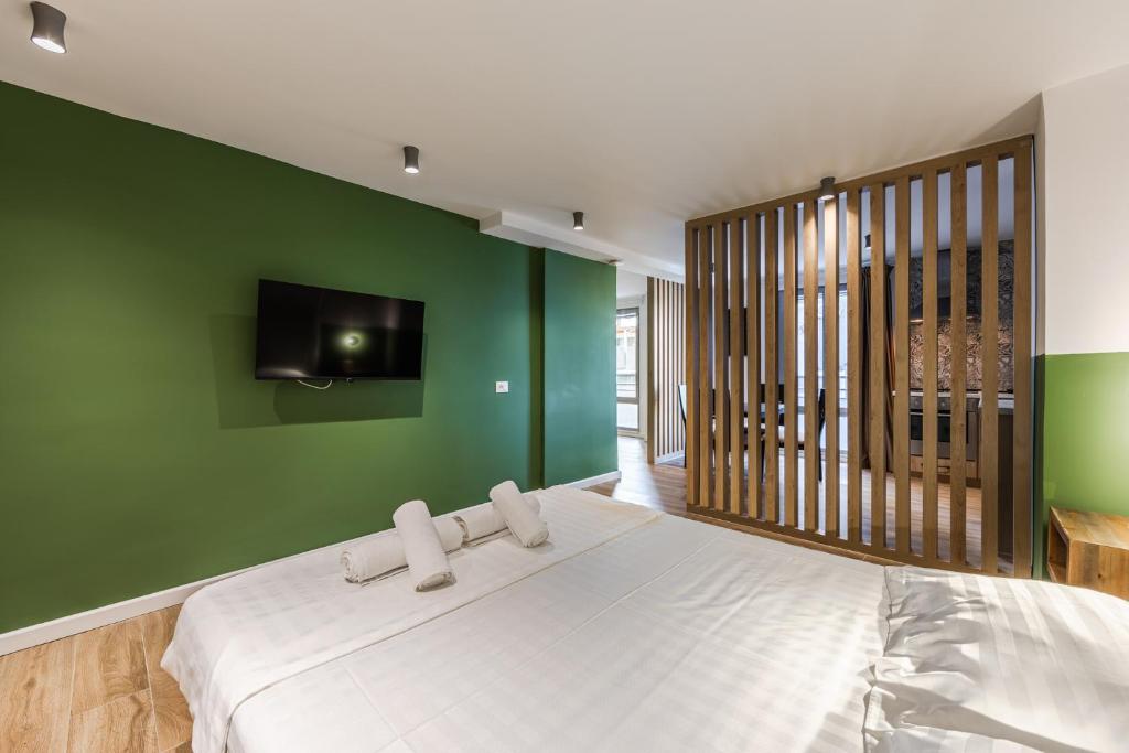 a bedroom with a white bed with a green wall at Love in Colours by PikHost in Durrës