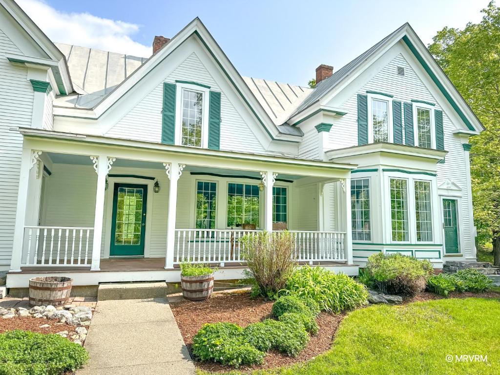 a white house with a porch and a yard at West Hill Farmhouse in Warren