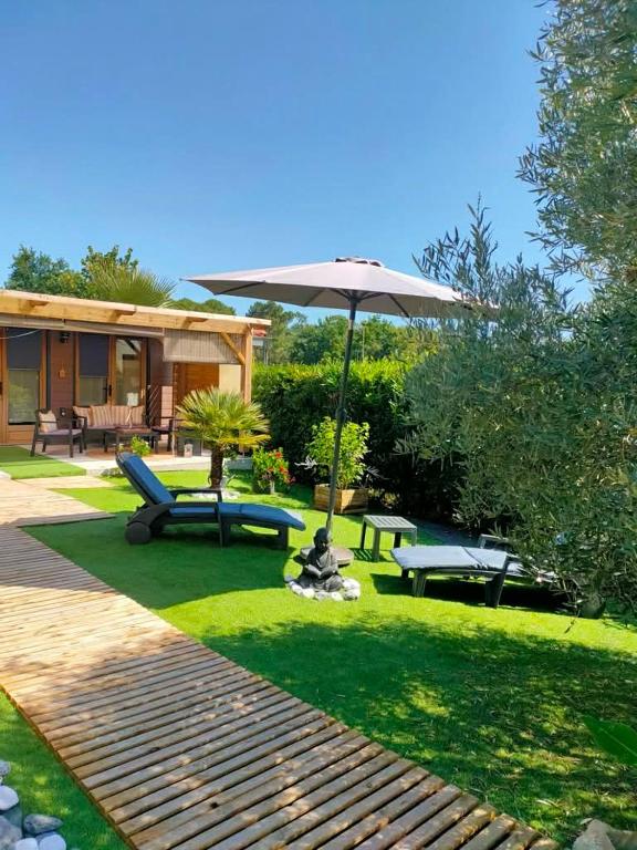 a garden with an umbrella and benches and a house at Chalet vacances avec jardin près d'Arcachon 2 personnes in La Teste-de-Buch