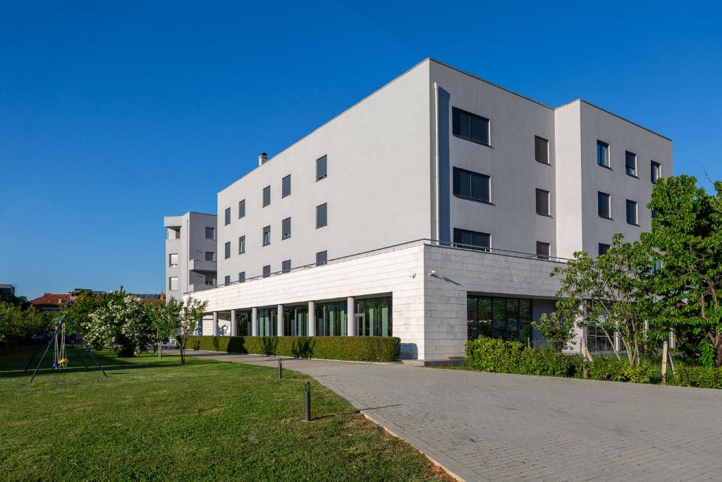 a large white building with a green lawn in front at Hotel Palace Medjugorje in Međugorje