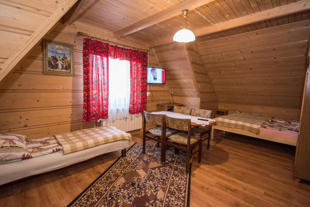 una habitación en una cabaña de madera con mesa y sillas en Wolne pokoje Maria Rzadkosz, en Gliczarów Górny