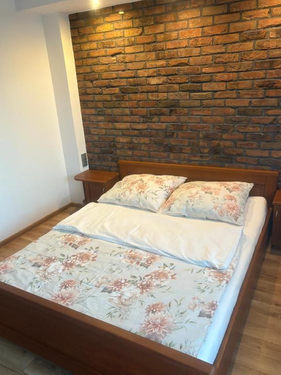 a bed in a room with a brick wall at Apartament Florynka in Florynka