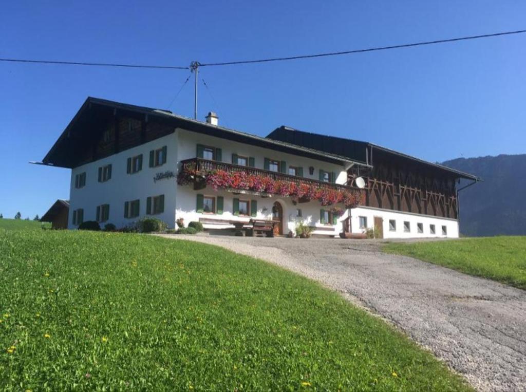 a large white building on a hill with a green field at Ferienwohnung Kollerlehen in Bischofswiesen