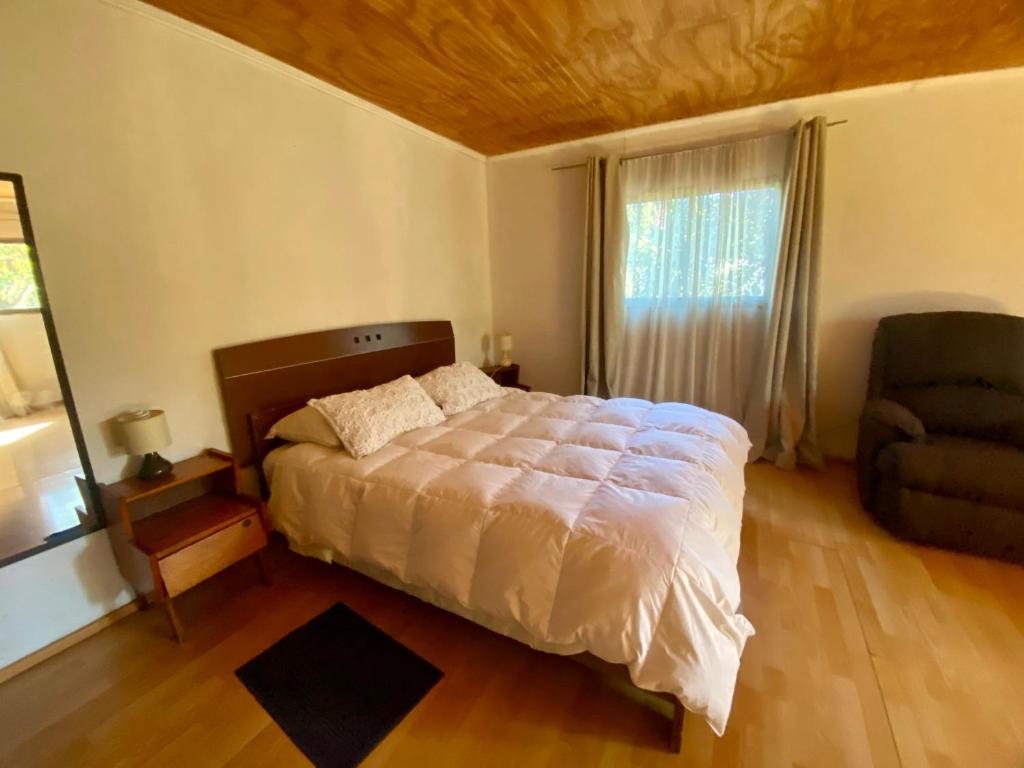 a bedroom with a bed and a chair and a window at Refugio Escondido in Isla de Maipo