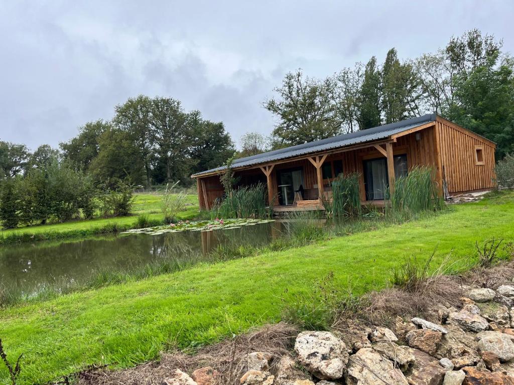 a wooden cabin on a hill next to a pond at Chalet in Fleury-sur-Loire