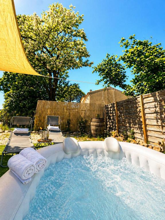 a hot tub in a backyard with two chairs at Bungalow jacuzzi & jardin privatif séjour détente au soleil in La Crau
