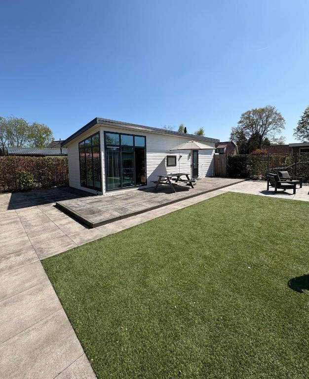 a house with a patio and a grass yard at Knus chalet Heidebloem Recreational purposes only in Putten