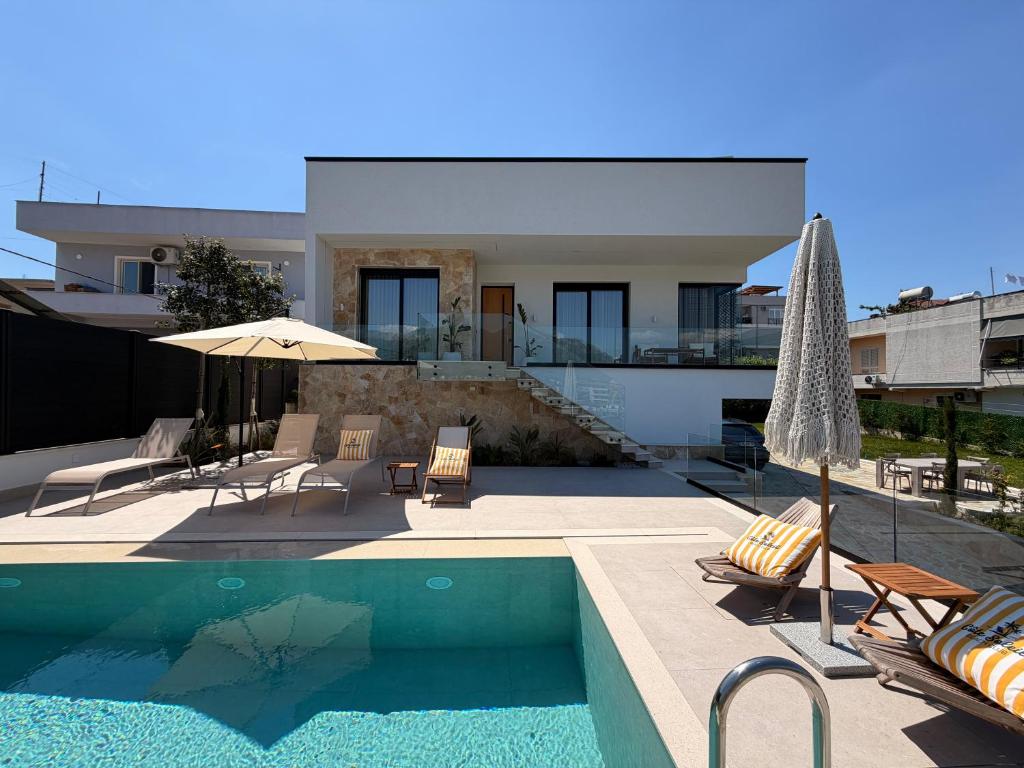 a house with a swimming pool with chairs and an umbrella at Vog Villa in Tirana