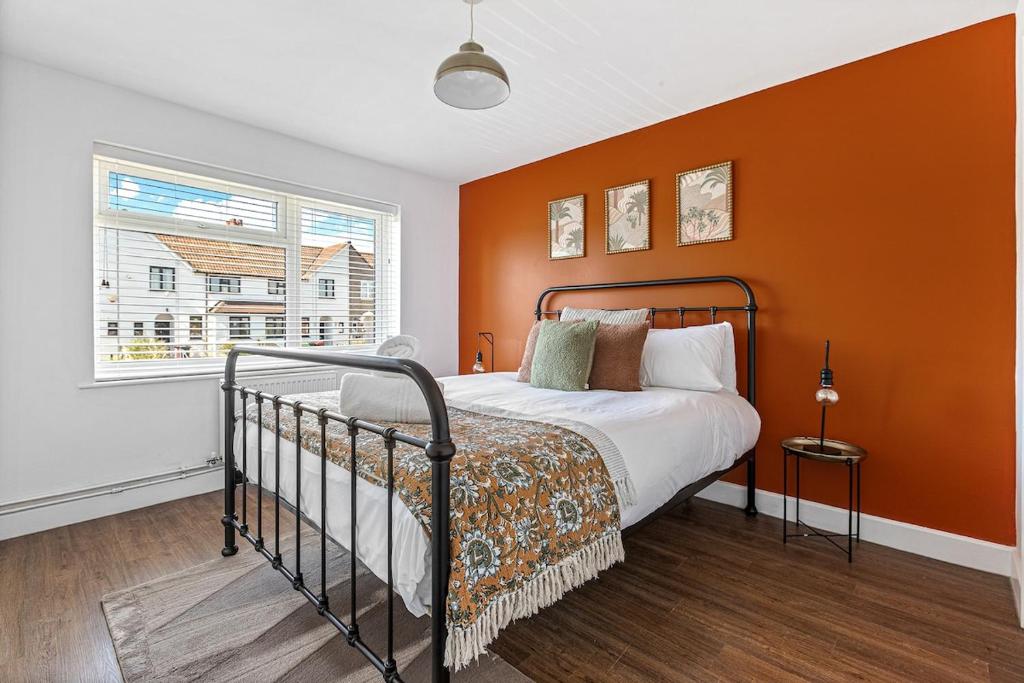 a bedroom with a bed with an orange wall at Modern 2-Bed House in Reading in Reading