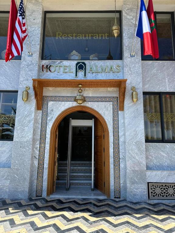 a building with an entrance to a hotel with two flags at Hotel Almas Meknes in Meknès