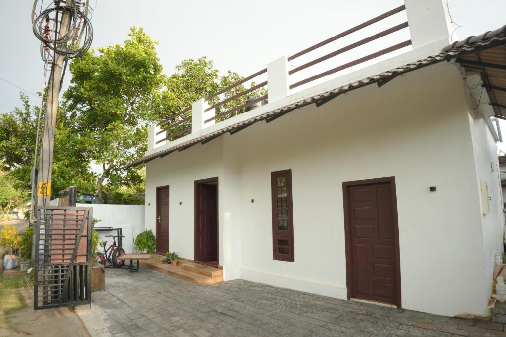 a white building with brown doors and a patio at Dune Hostel - Dune Homestay in Alleppey