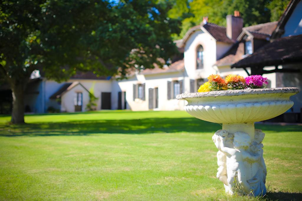 a white bird bath with flowers in a yard at Le Clos du Cerf in Cellettes