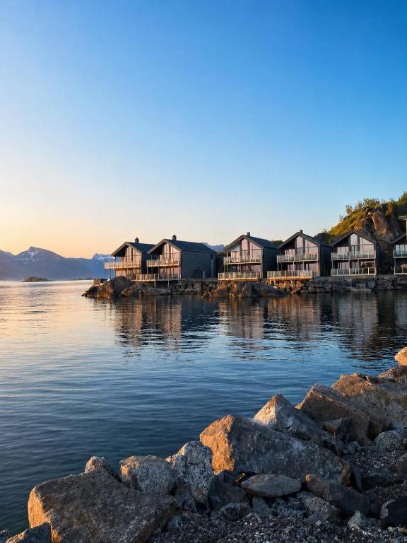 a row of houses on the shore of a body of water at Hamn i Senja - Private top apartment with seaview in Senja