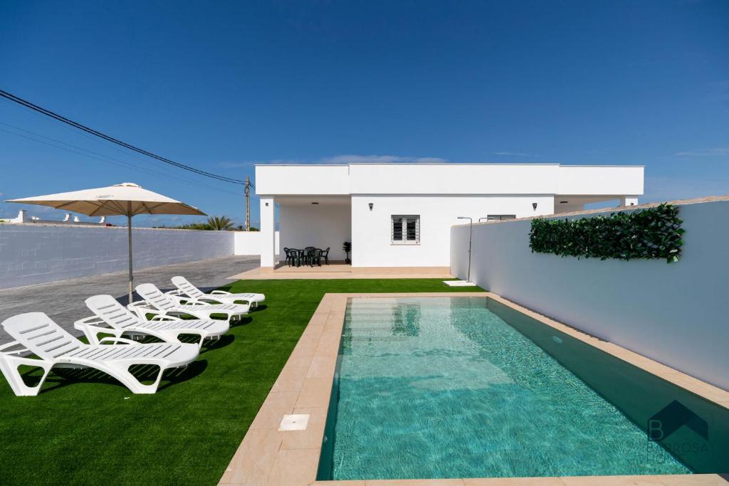 a villa with a swimming pool and lounge chairs at Ginebra A BARROSAHOME in Novo Sancti Petri