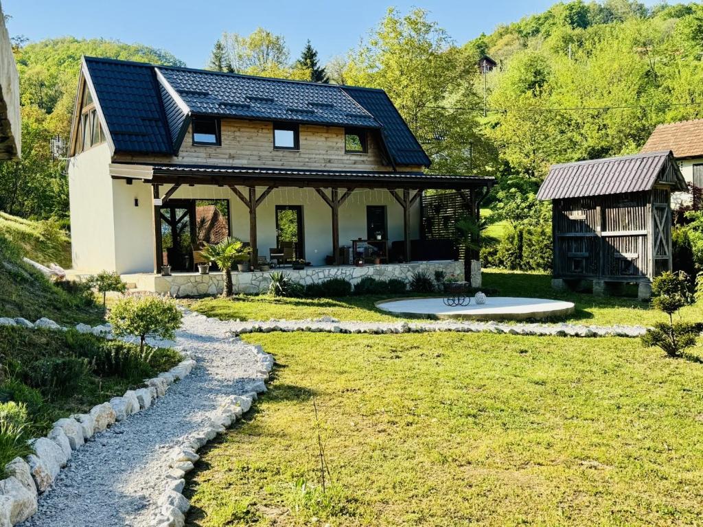 a house with a slate roof and a gravel driveway at Green Hills - Holiday Home & Events in Kamenica