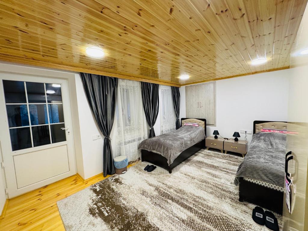 a bedroom with two beds and a wooden ceiling at The House 39 in Sheki