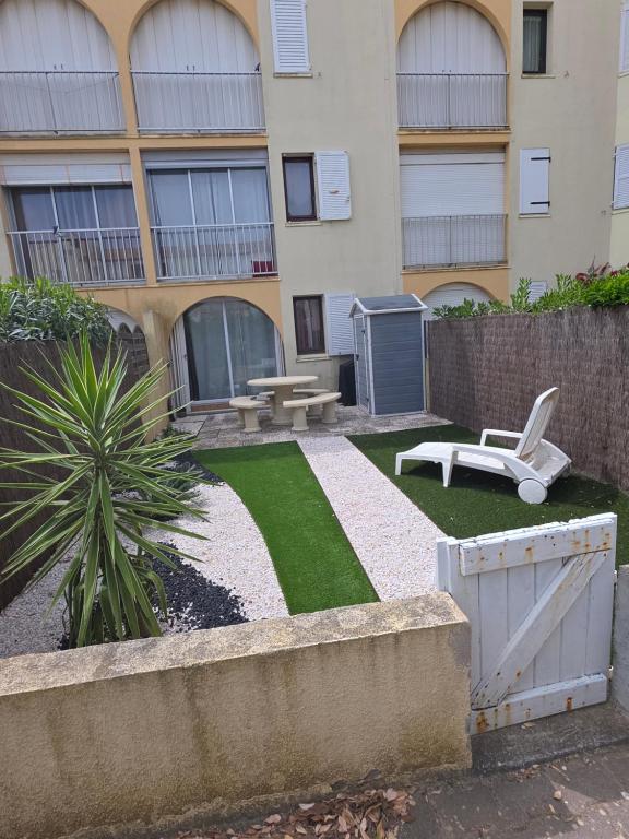 a building with a yard with a chair and a table at Appartement T2 avec son rez de jardin de 40 m2 5 couchages 250m de la plage et 15km de l'Arena in Narbonne-Plage