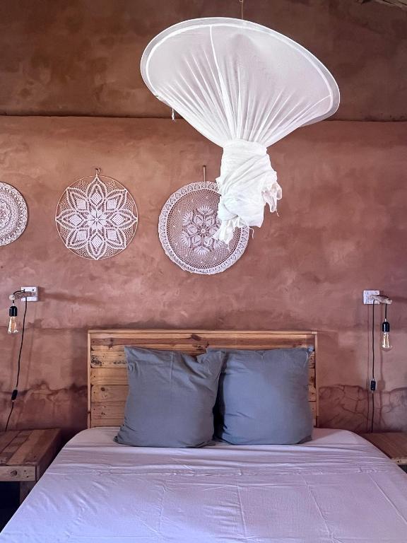 a bedroom with a bed with a chandelier above it at Mbin Maak du Saloum in Mar Lodj