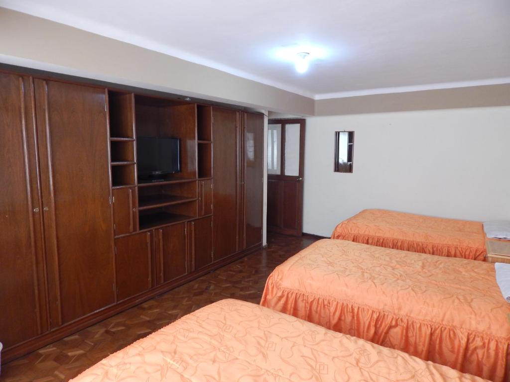 a hotel room with two beds and a tv at Casa de Huespedes Isabella in Sucre