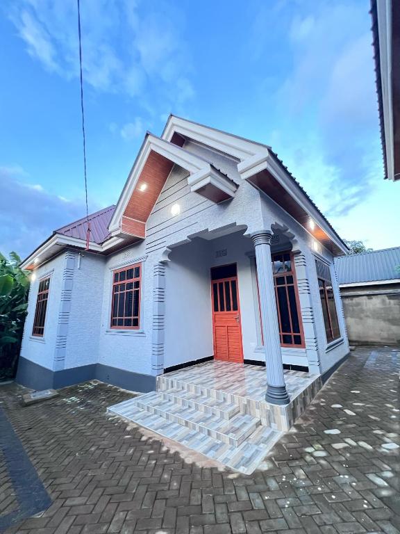 a small white house with a red door at Jk Suites Karatu in Karatu