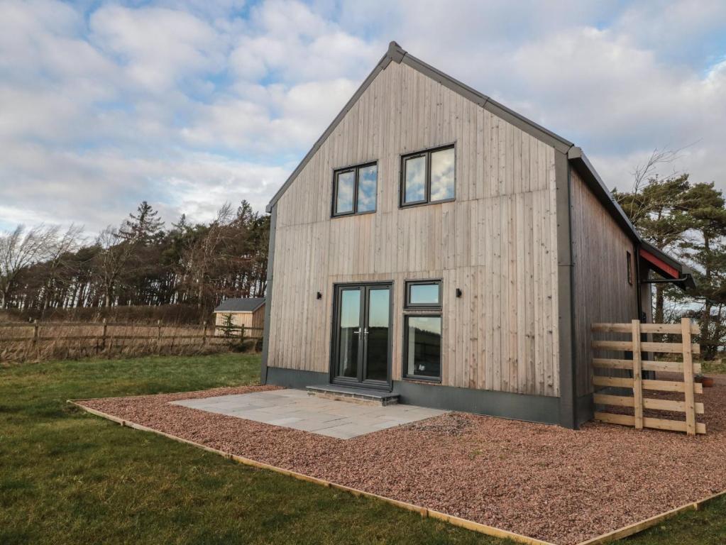 a large wooden house with windows on a field at Harvest Cottage 2 in Berwick-Upon-Tweed