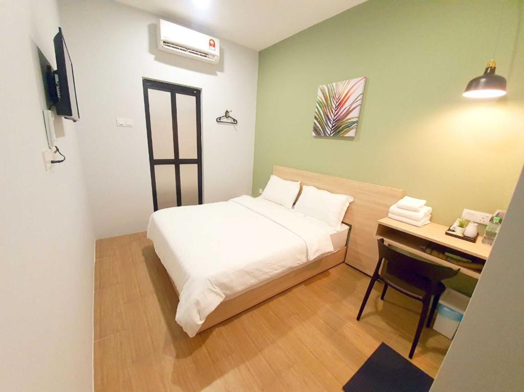 a small bedroom with a bed and a desk at Hotel O Green Home Hotel in Sepang