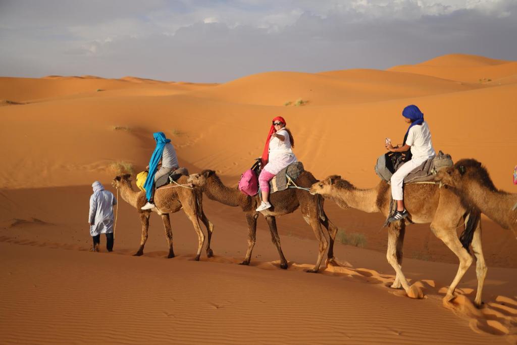 a group of people riding on camels in the desert at La Source Desert Camp in Adrouine