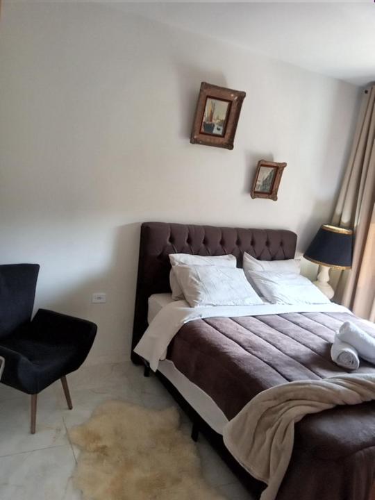 a bedroom with a large bed with a chair and a lamp at Pousada Casa Terra de Pinheiros in Santo Antônio do Pinhal