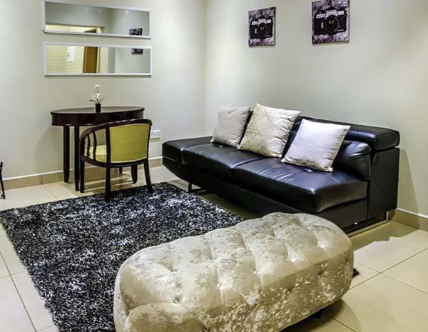 a living room with a black leather couch and a table at Hillview inn hotel in Serowe