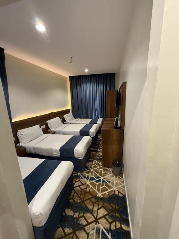 a row of four beds in a hotel room at فندق العلاء 5 in Ajyad