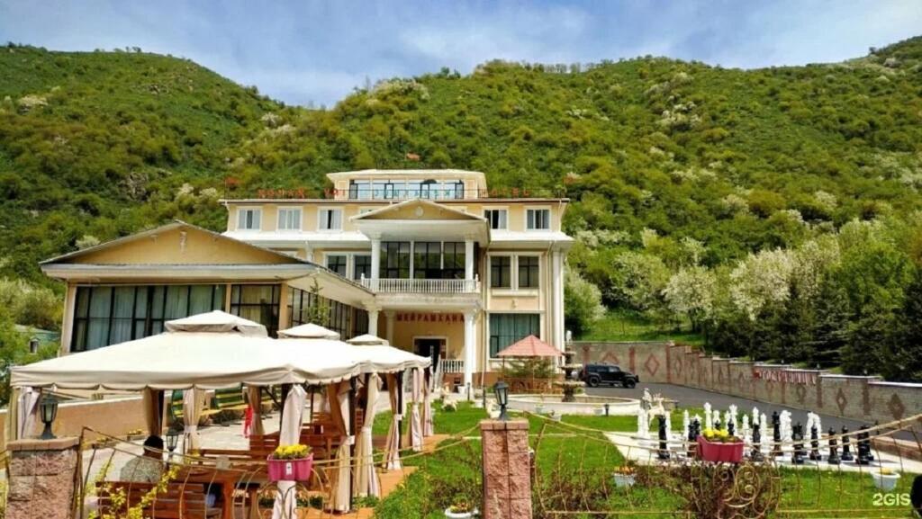 a large house with umbrellas in front of it at Edelweiss in Almaty