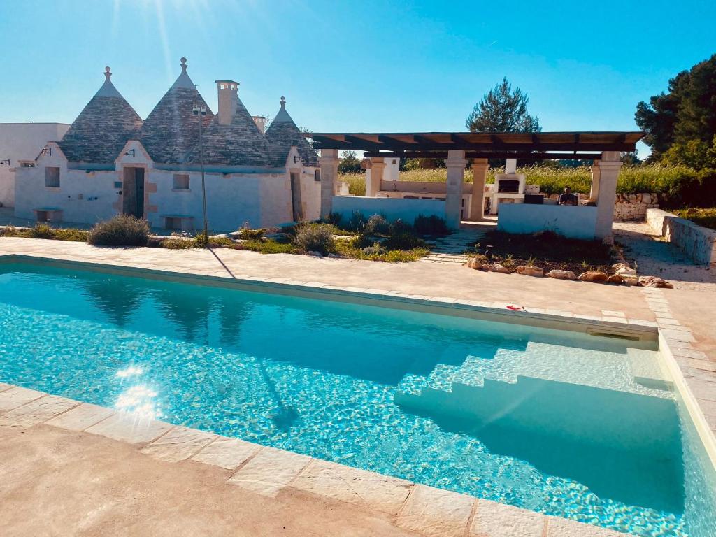 a swimming pool in front of a house at Luxury Trulli di Giulia, exclusive villa with private pool in Valle d'Itria Ostuni - BR, Puglia in Ostuni