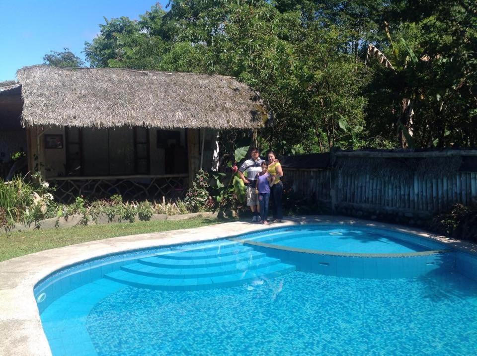 two people standing next to a small swimming pool at Hostería Mindo Samay Juku in Mindo