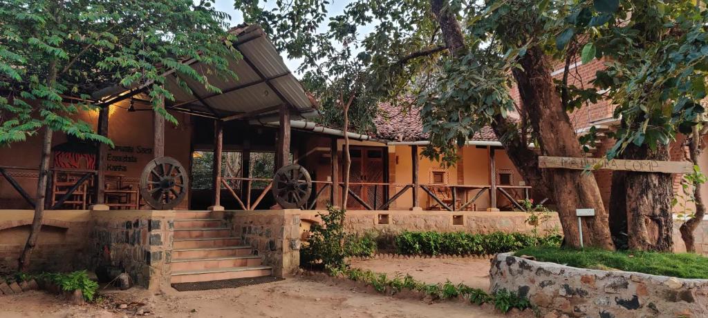 a house with a tree and stairs in front of it at Surwahi Social Ecoestate Kanha in Kānha