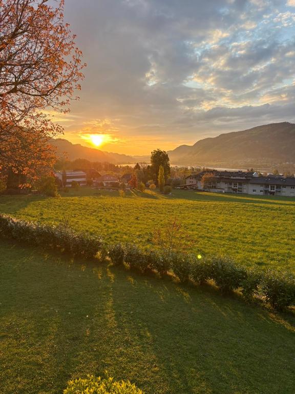 a field with the sun setting in the distance at Ferienwohnung KaRo in Bodensdorf