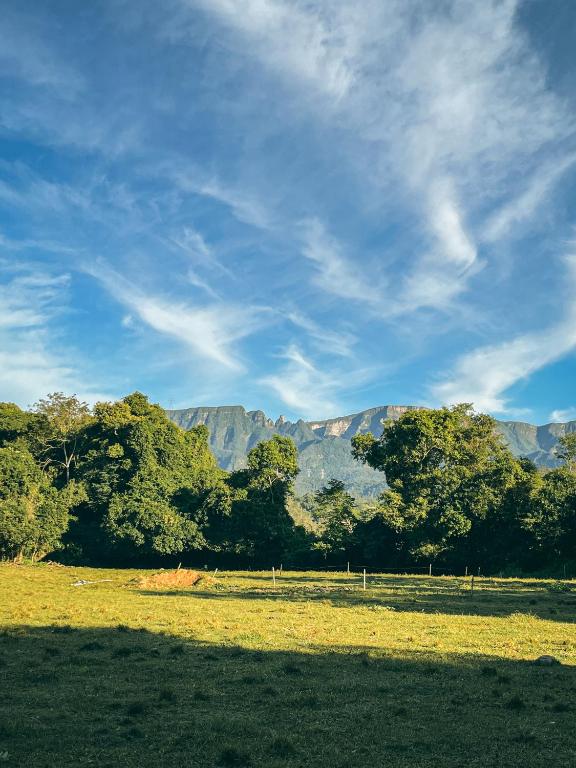 a field with trees and mountains in the background at Camping Rio do Rastro in Lauro Müller