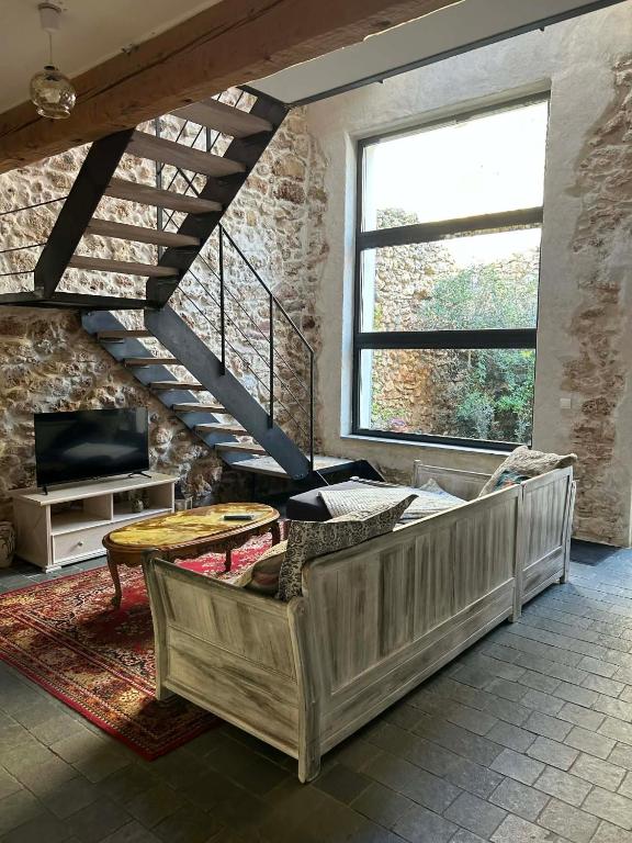a living room with a couch and a tv at L'Amandine in Puisserguier