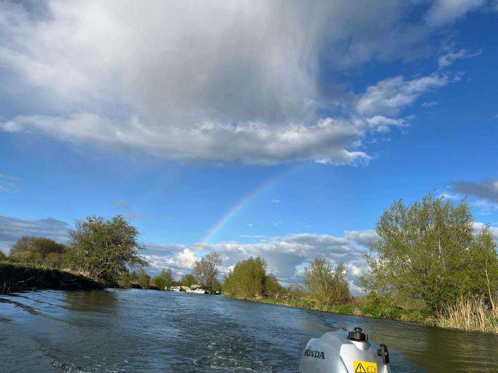 a boat on a river with a rainbow in the sky at Pop Bell tent in Radcot