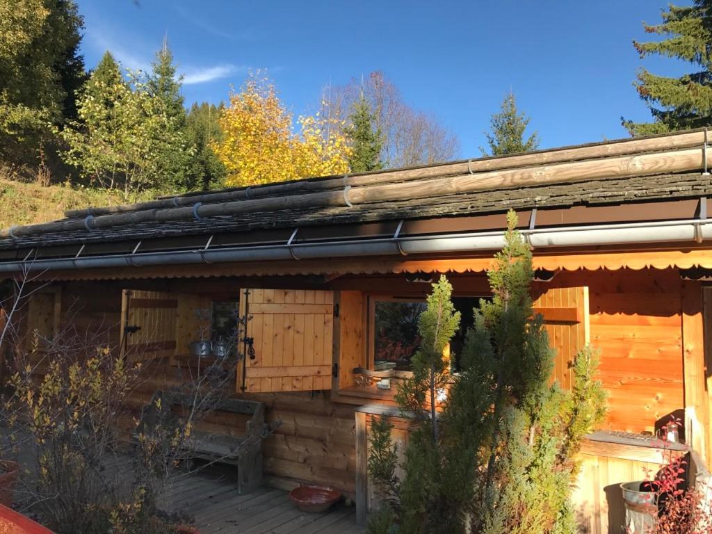 a wooden cabin with a deck in the woods at Chalet ANTARÈS in Manigod
