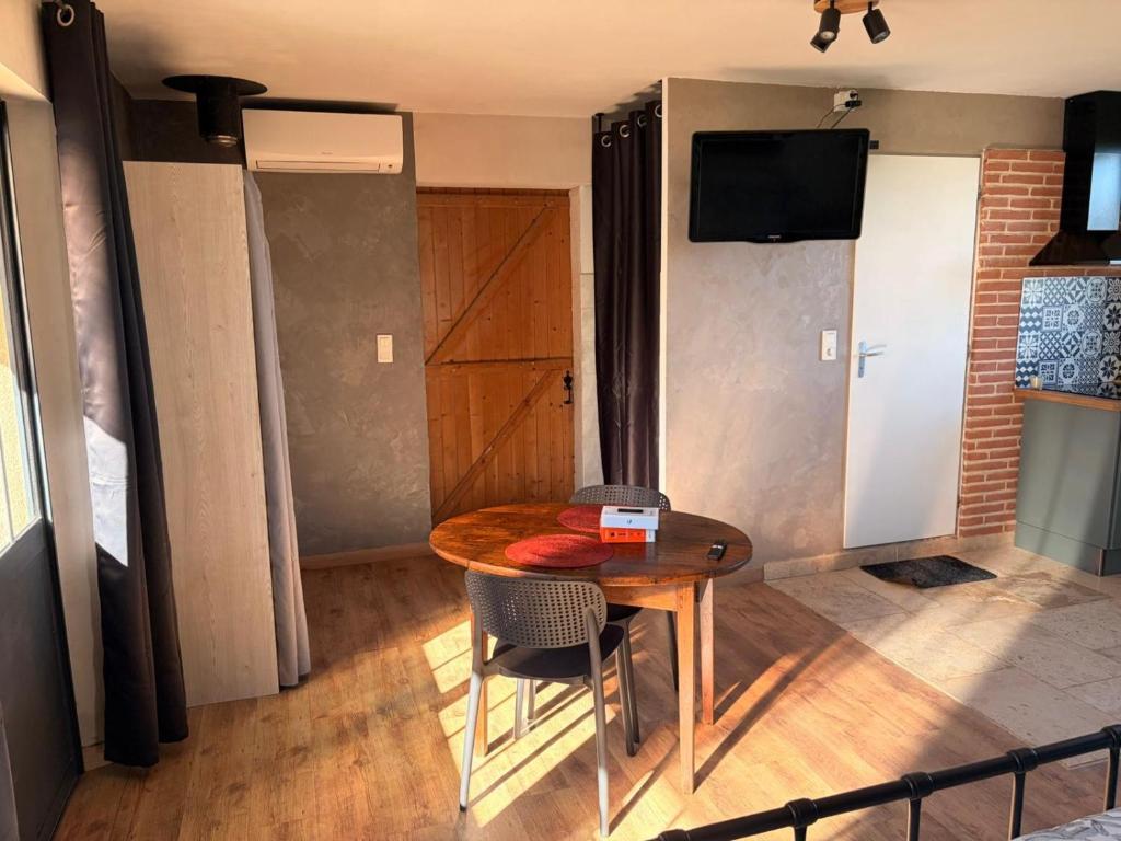 a table and chairs in a room with a television at La Perle Rare in La Barthe