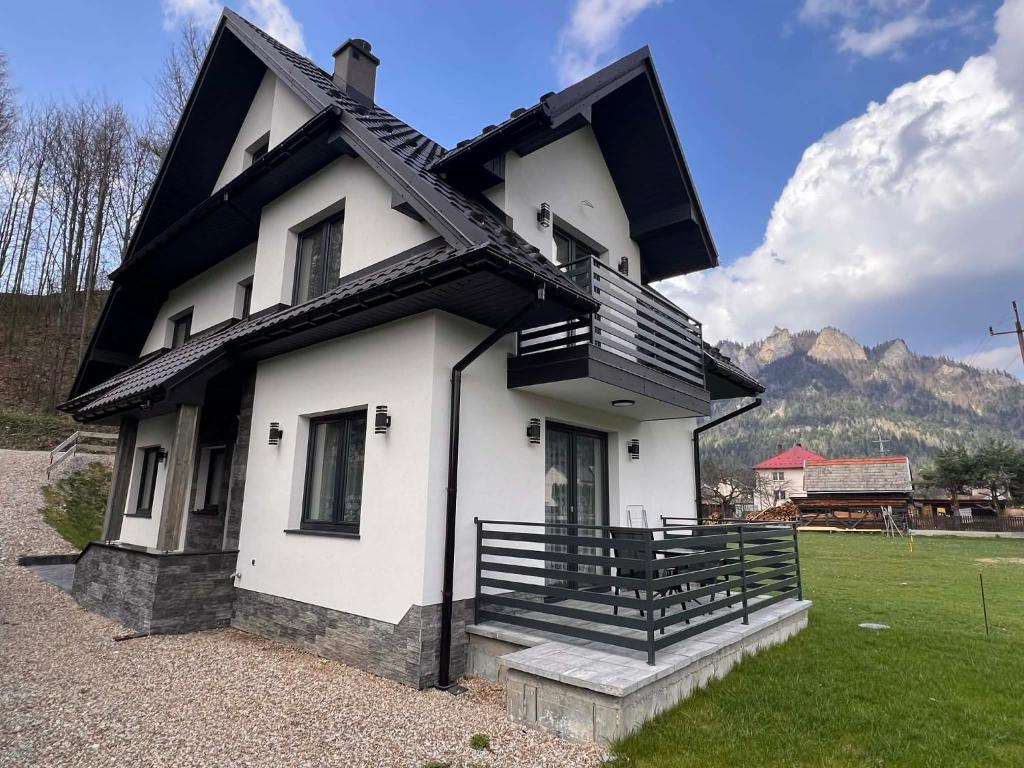 a white and black house with mountains in the background at Willa Górski Relaks in Sromowce Niżne