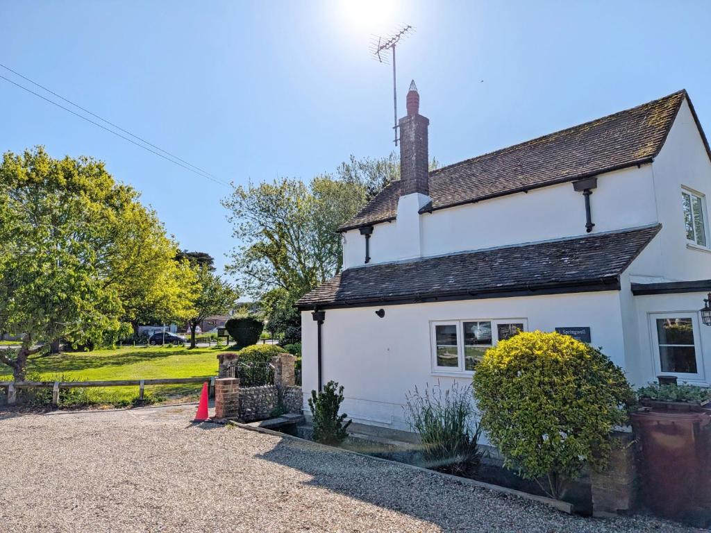 a white cottage with a gravel driveway at Springwell , West Wittering in West Wittering