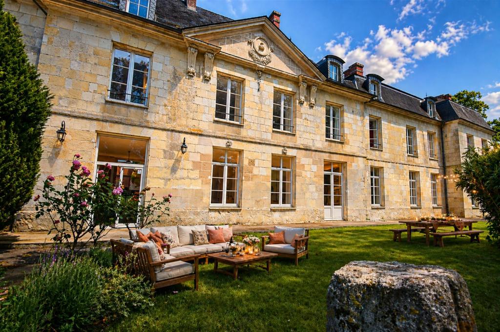a large stone building with couches and tables in a yard at Château de Ravenel in Ravenel