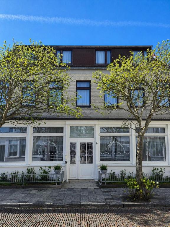 a building with a white door and two trees at Pension Haus Weierts in Norderney