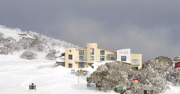 a large building in the snow in front of a mountain at Chalet Hotham 8 in Mount Hotham